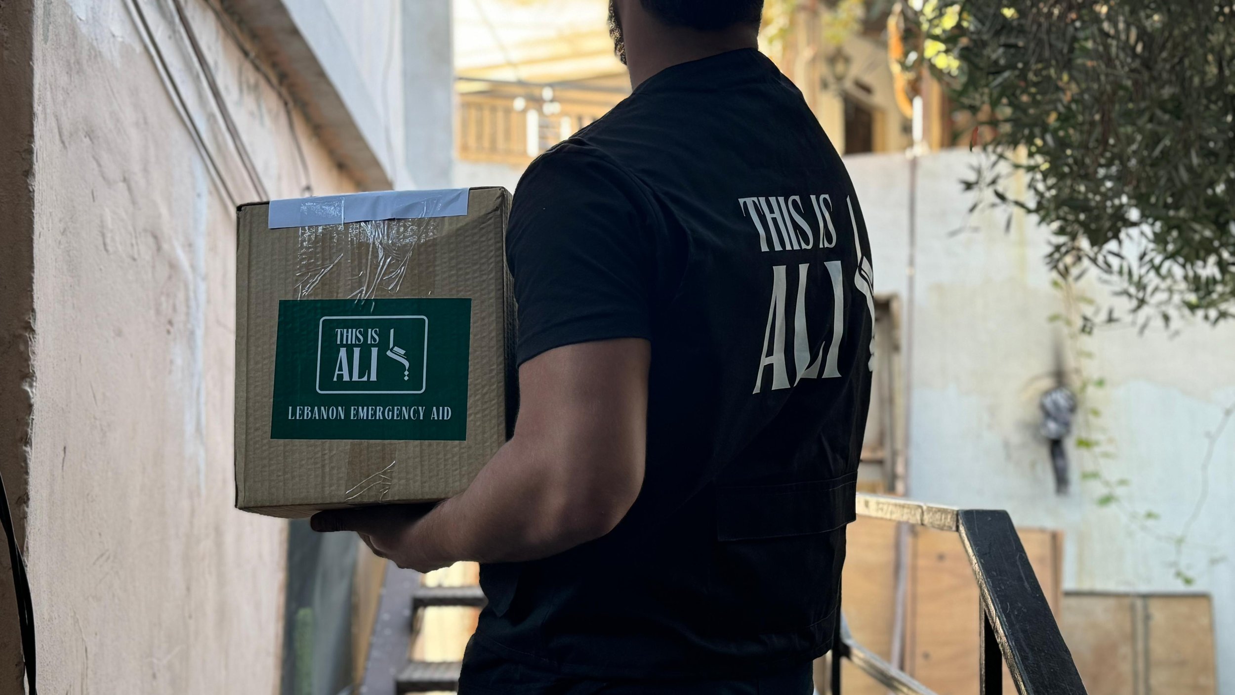 A TIA volunteer carrying a box marked Lebanon Emergency Aid during a relief delivery.